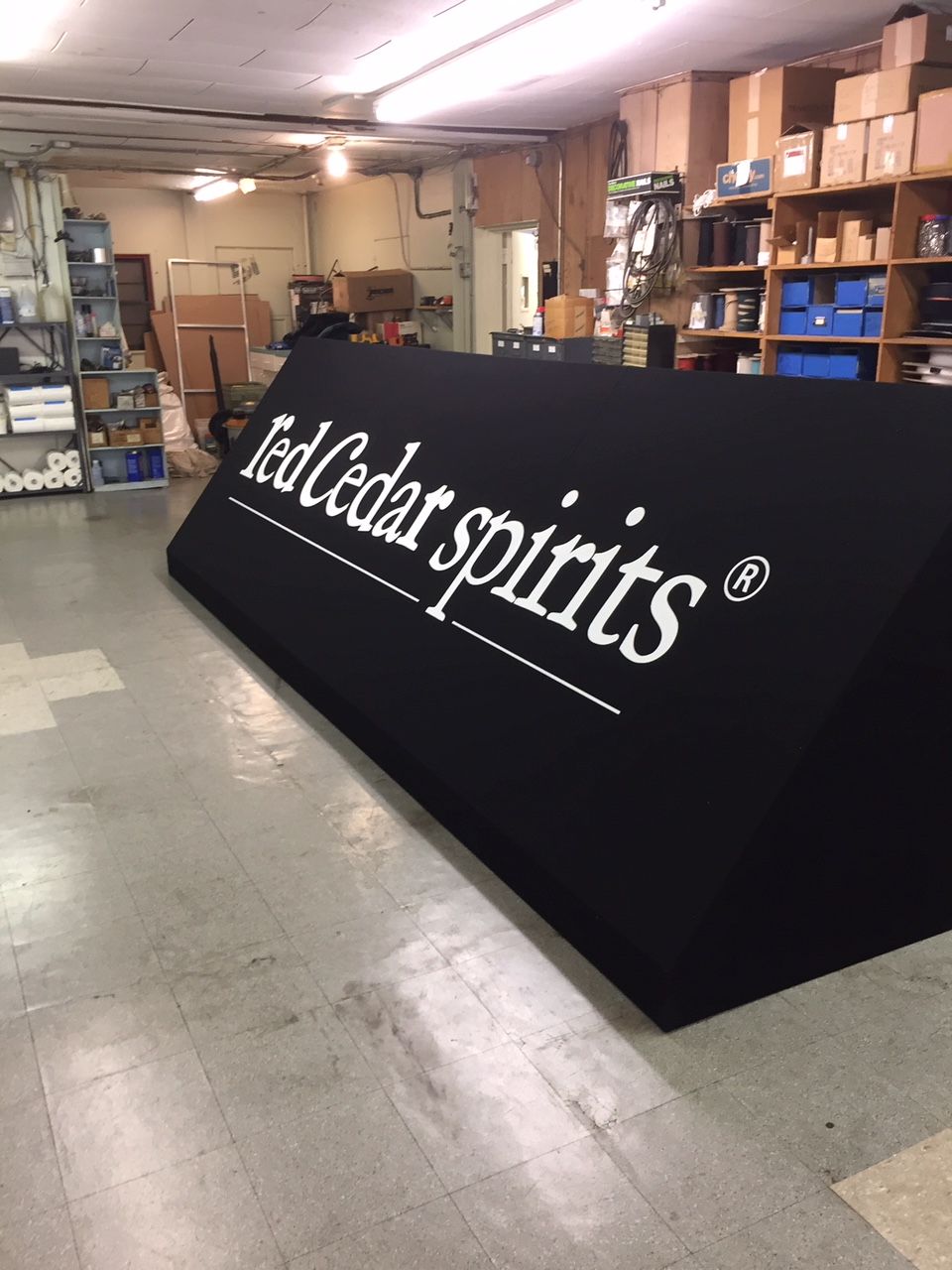 Black Red Cedar Spirits sign in a warehouse with shelves and boxes in the background