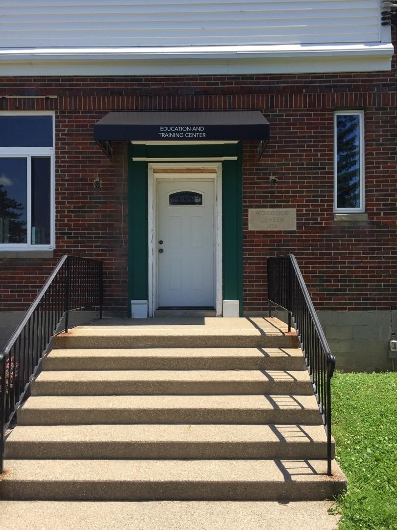 The front door of a brick building with stairs leading up to it.
