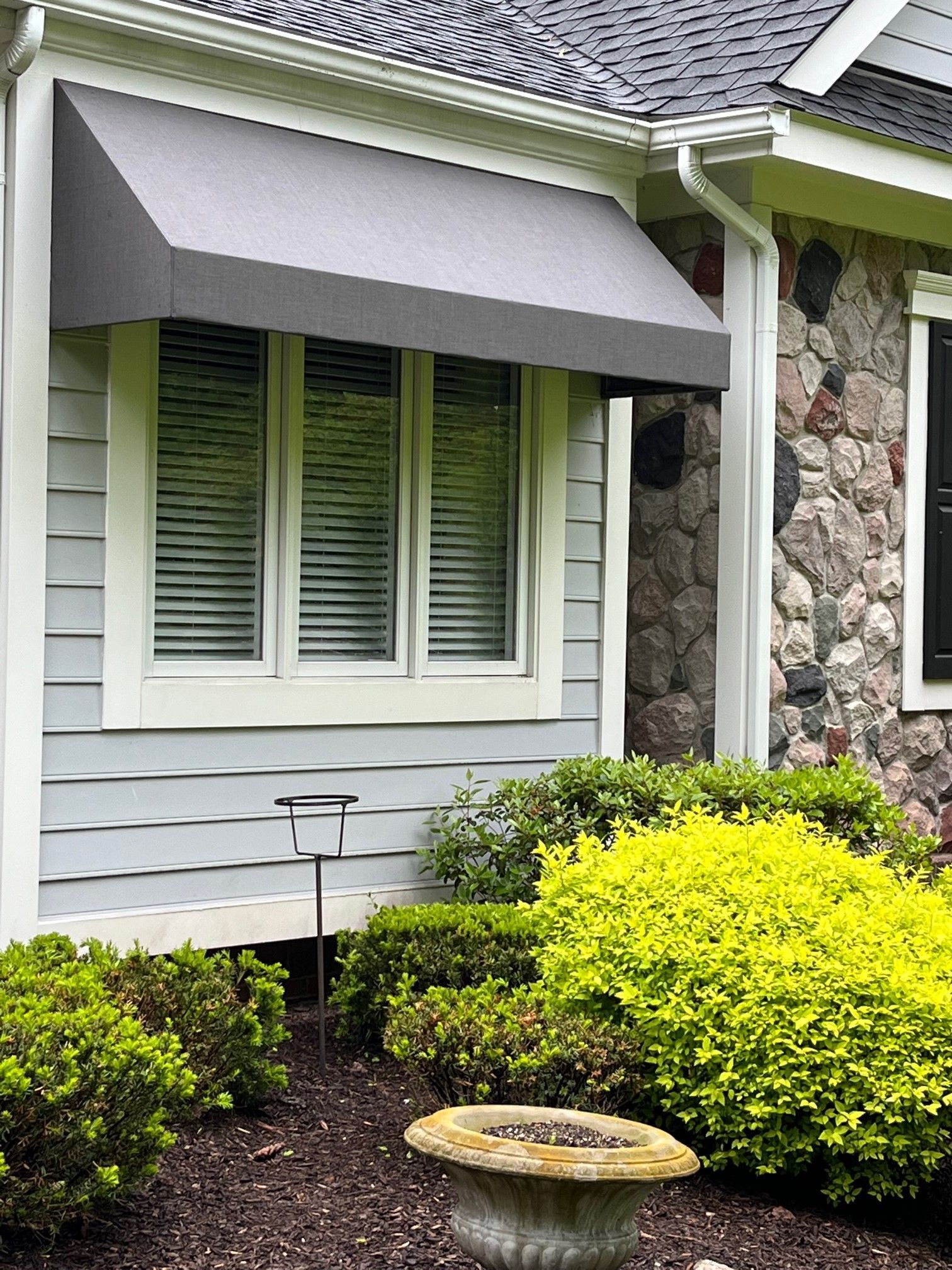 A house with a gray awning over a window.