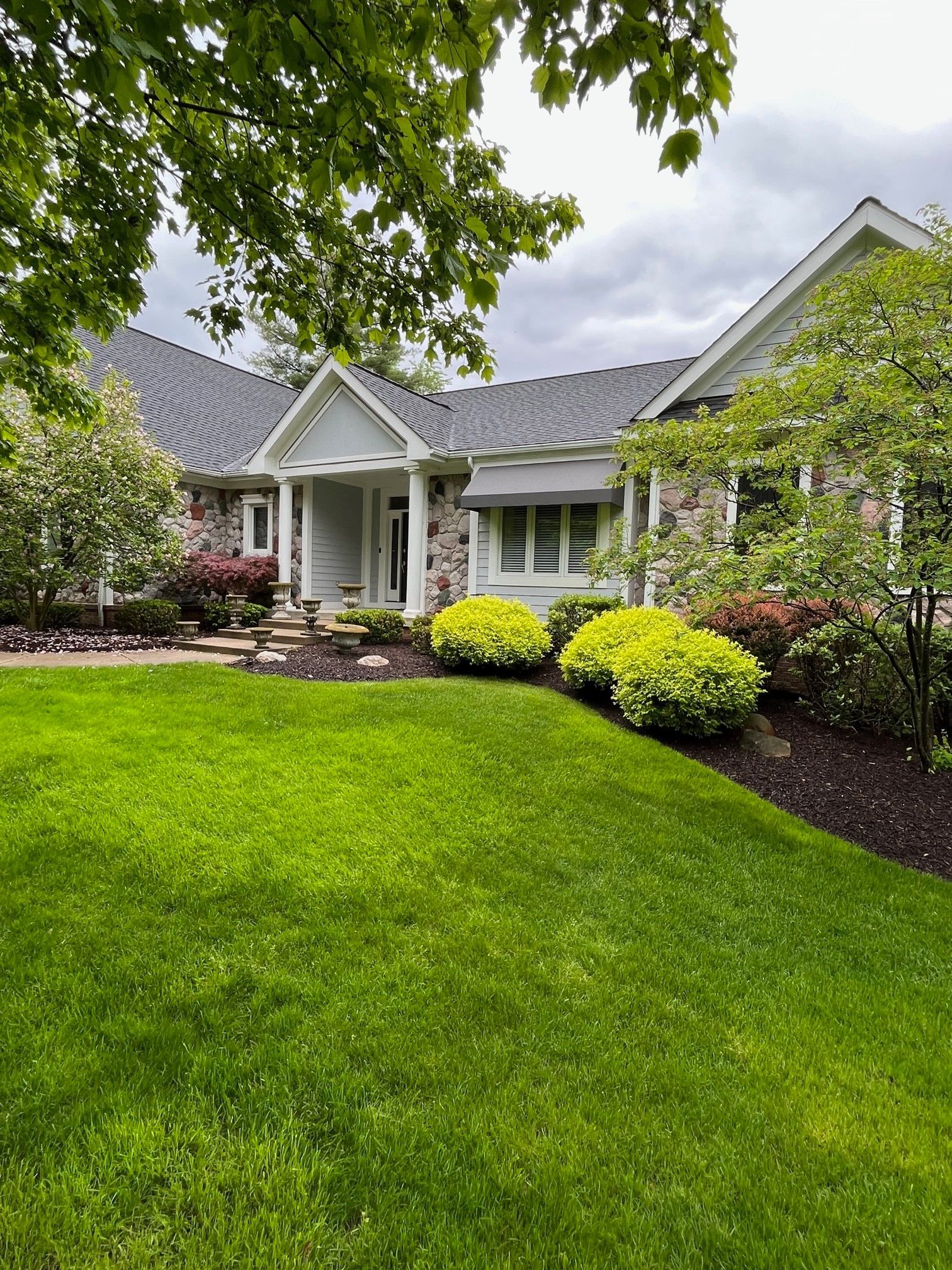 A large white house with a large lush green lawn in front of it.