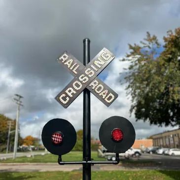 A railroad crossing sign with a red light on it.