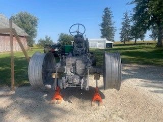 Rear view of a gray vintage tractor on jack stands, outdoors in a yard.