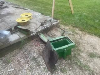 Green metal utility box with open lid and debris on a concrete surface next to grass.