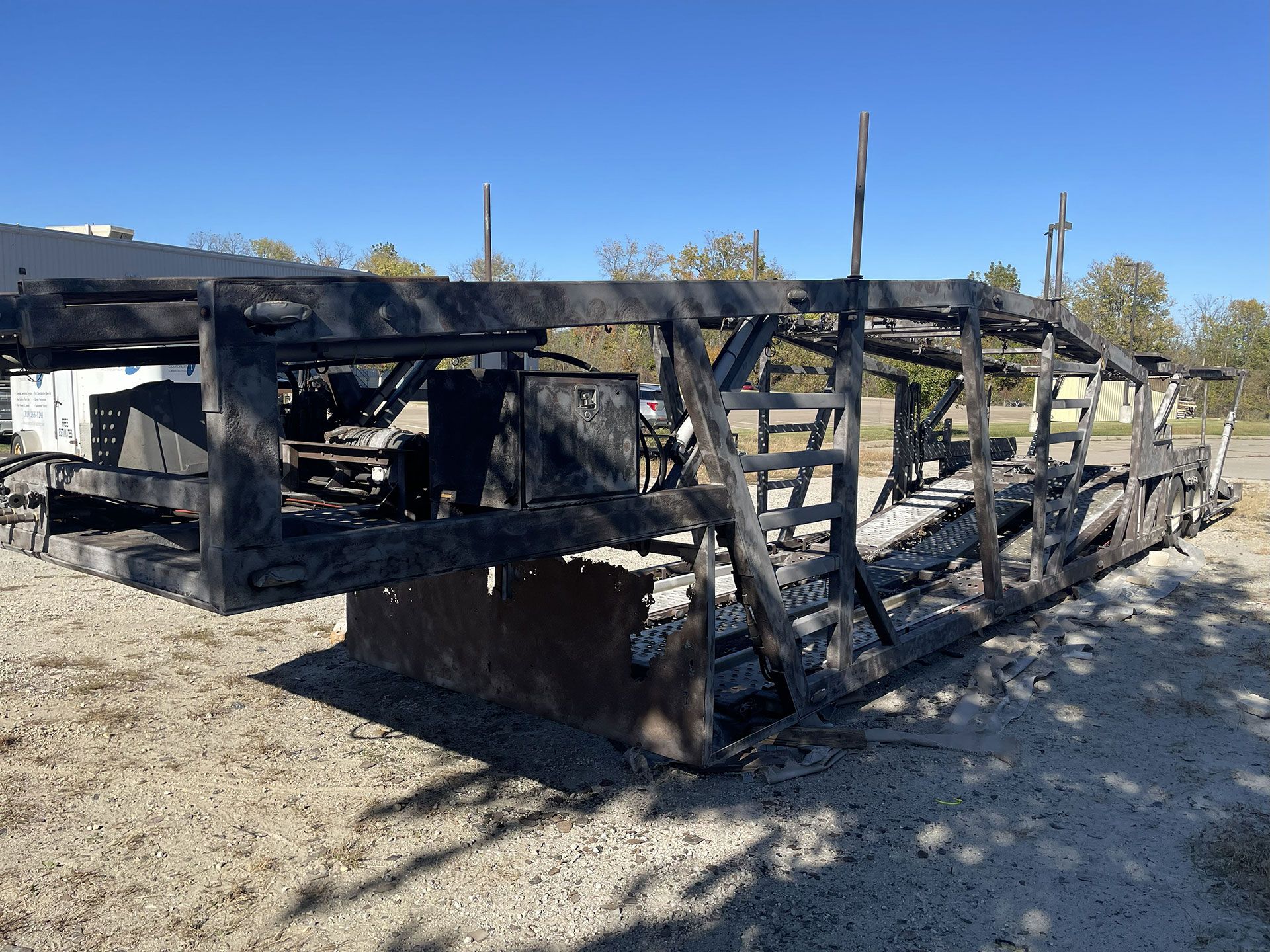 Charred remains of a recreational vehicle; the structure is black against a clear blue sky.