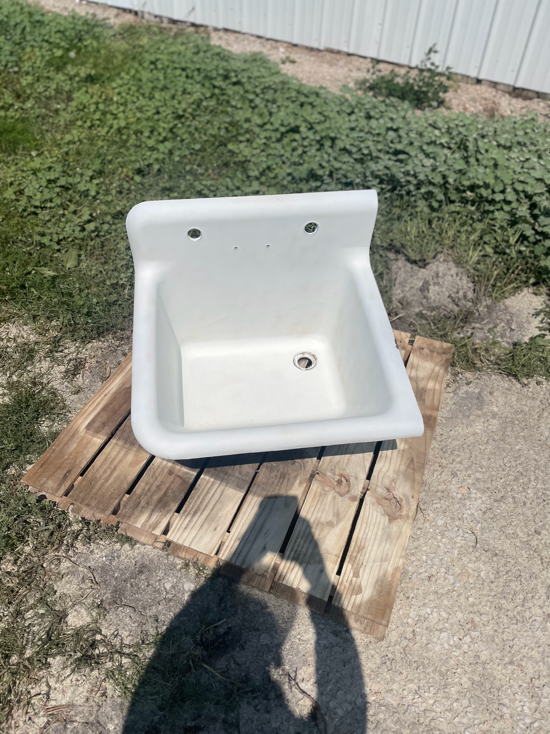 A white sink is sitting on a wooden pallet