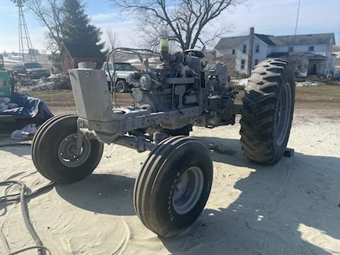 an old tractor is sitting on top of a dirt field