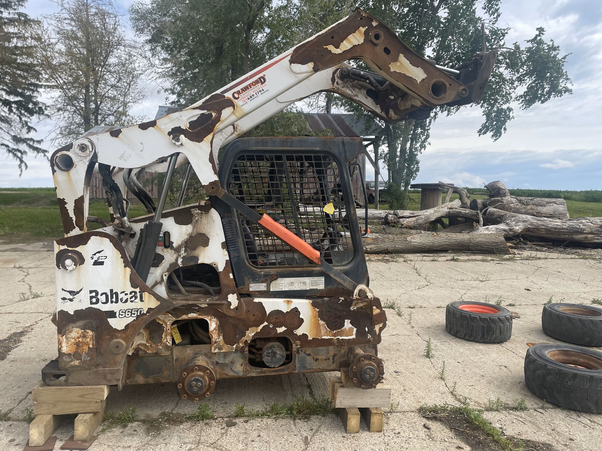 A bobcat is sitting on a wooden pallet in a field