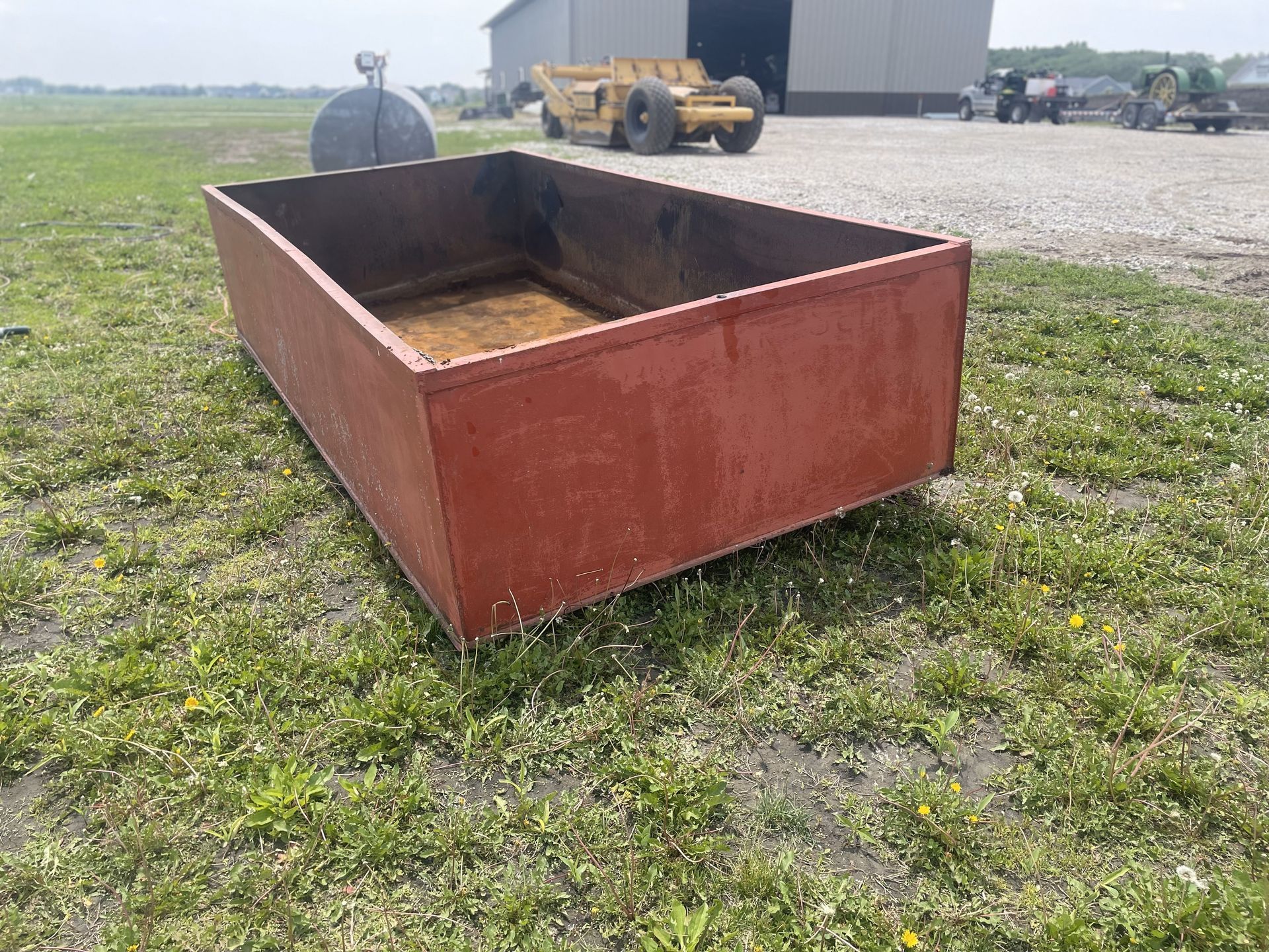 A large metal box is sitting on top of a lush green field.