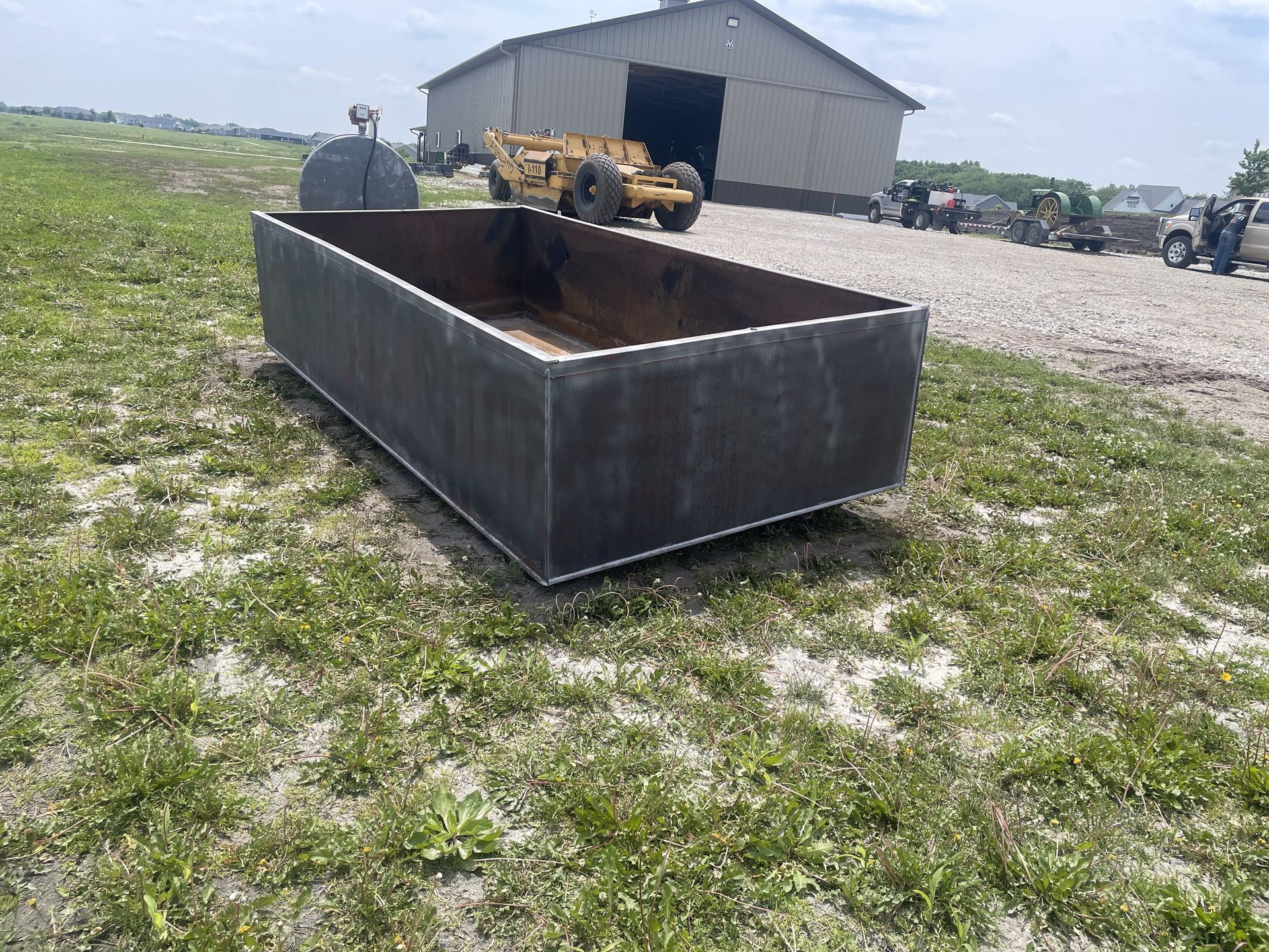 A large metal box is sitting in the grass in front of a building.