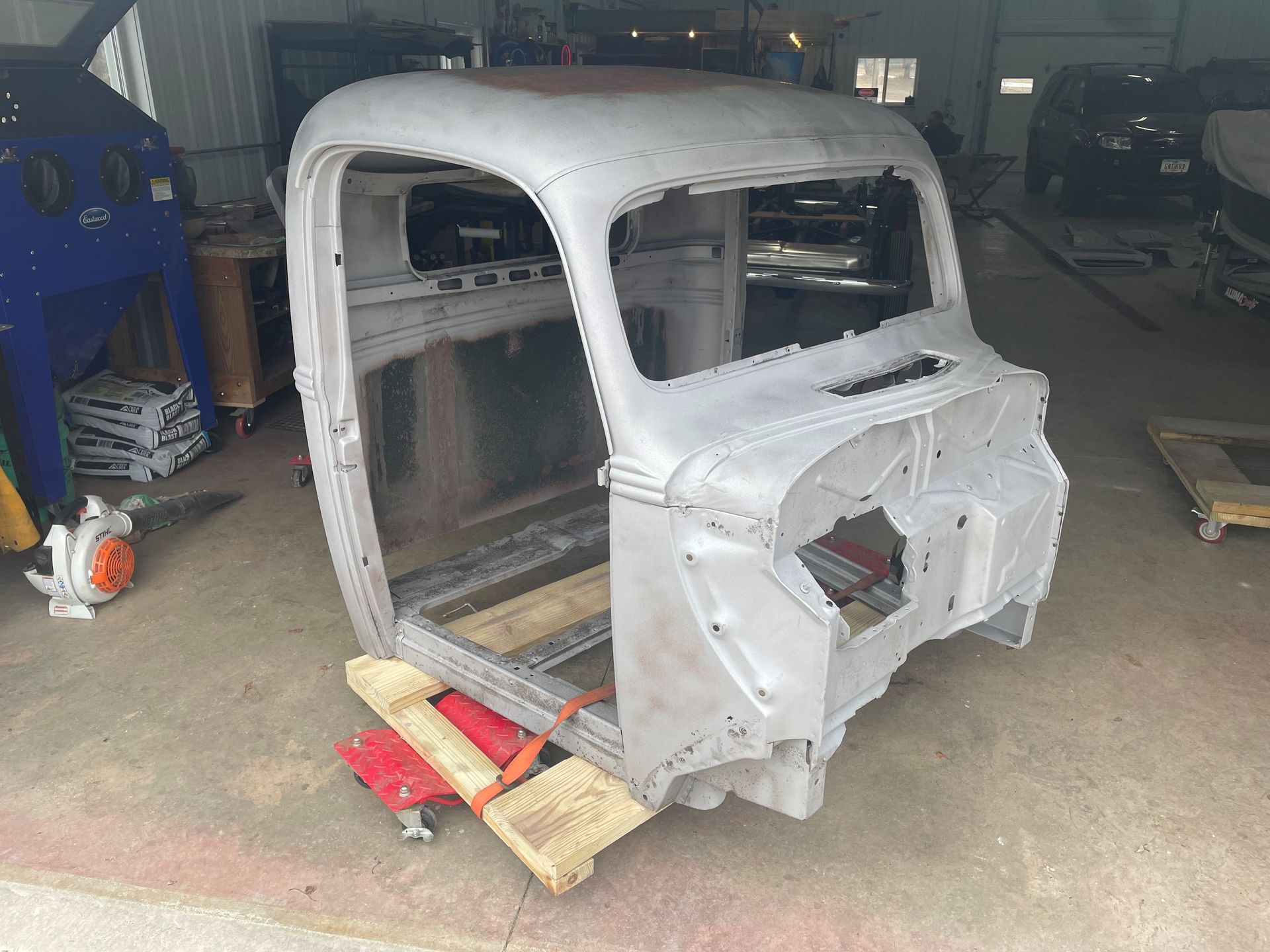 A truck body is sitting on a wooden dolly in a garage.