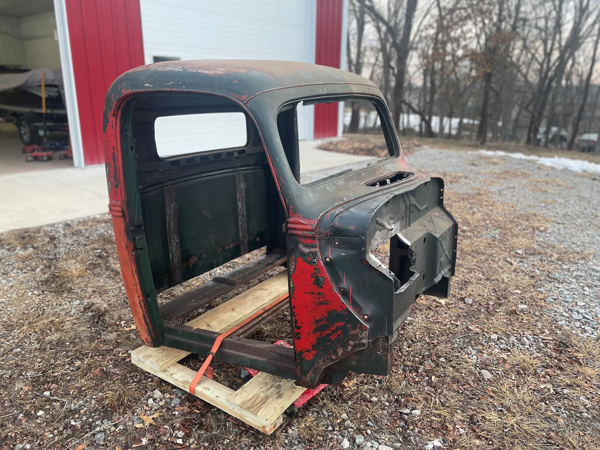 A truck cab is sitting on a wooden pallet in a garage.