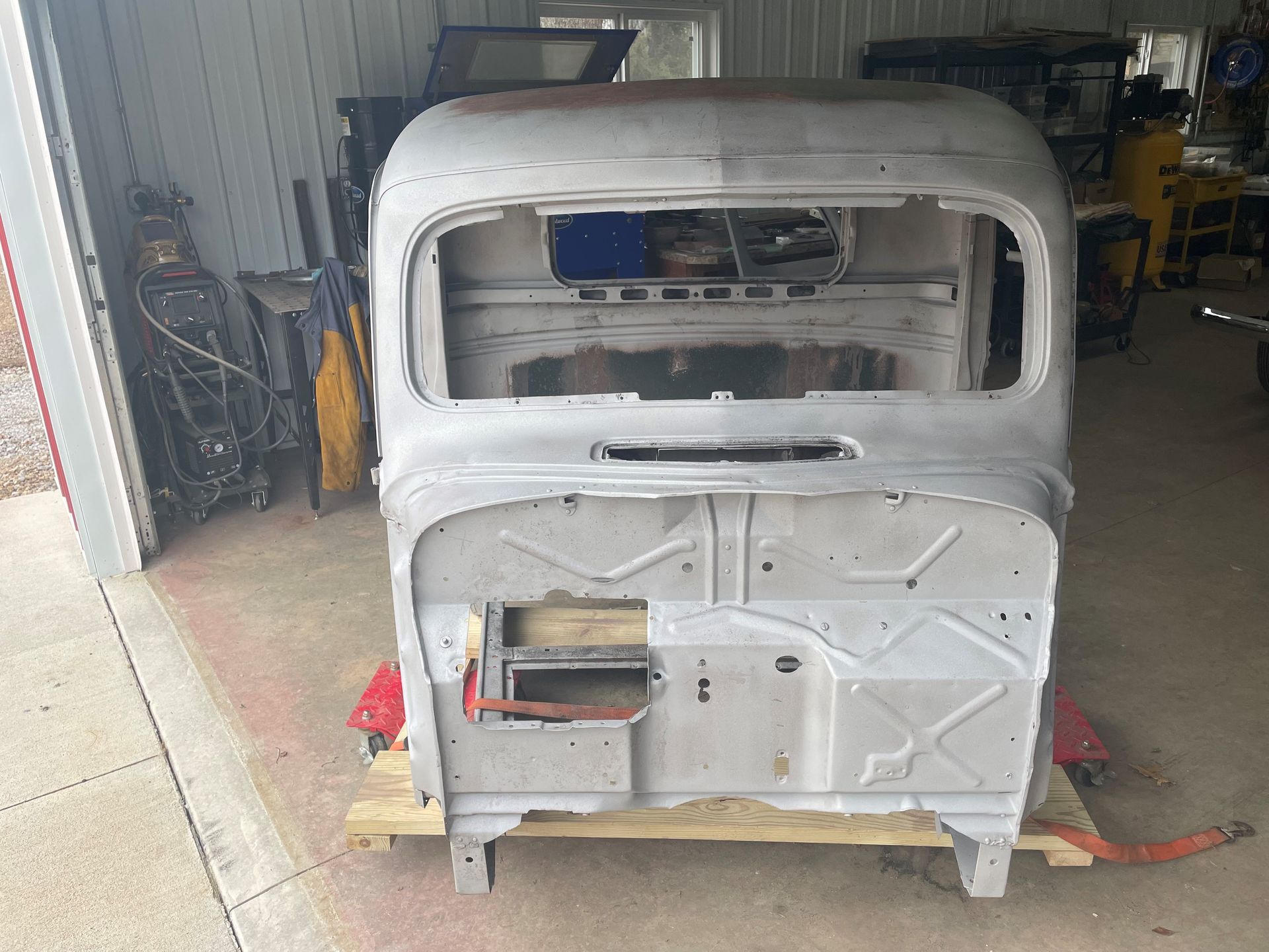 A truck cab is sitting on a wooden pallet in a garage.