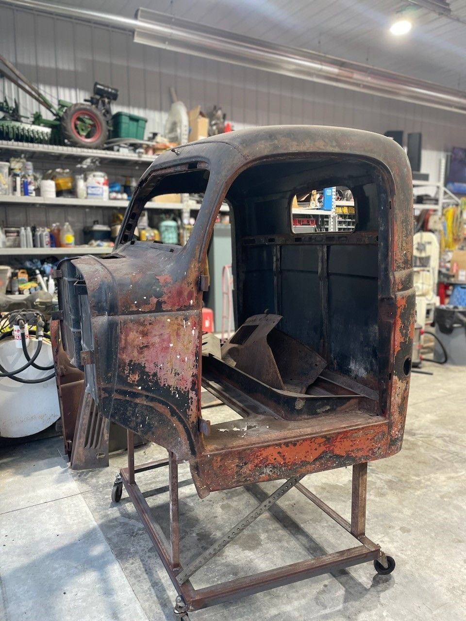 a rusty old truck cab is sitting on top of a metal stand in a garage