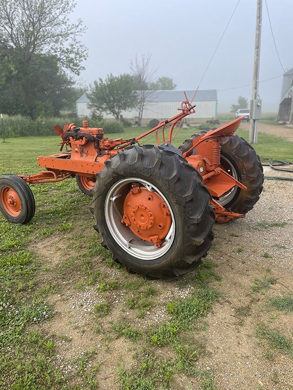 an old orange tractor is parked in a grassy field