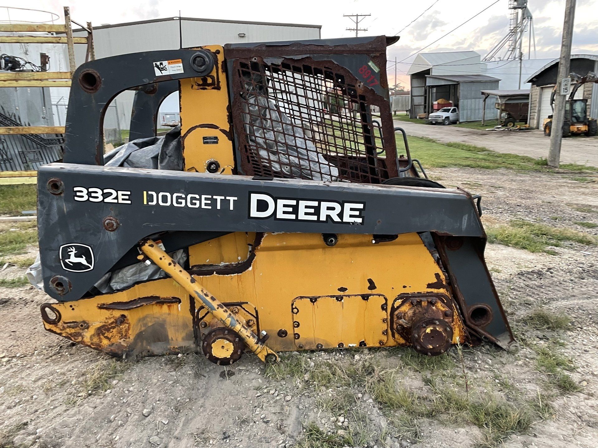 a yellow and black deere skid steer is parked in the dirt