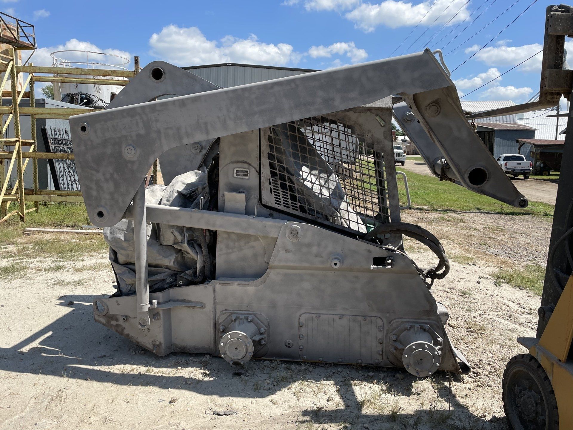 A cat skid steer is parked on the side of the road in the snow