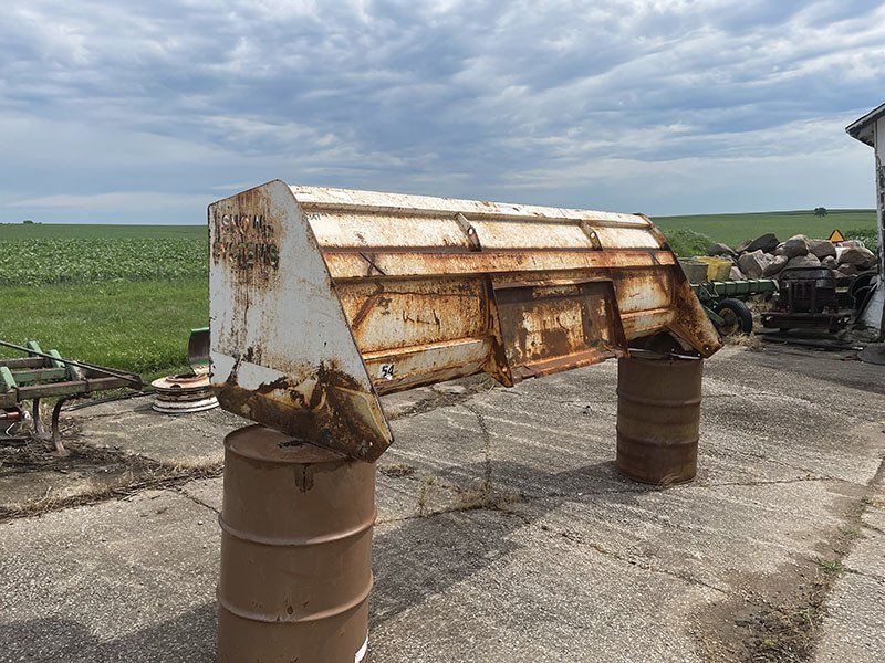 a rusty piece of metal is sitting on top of a rusty barrel