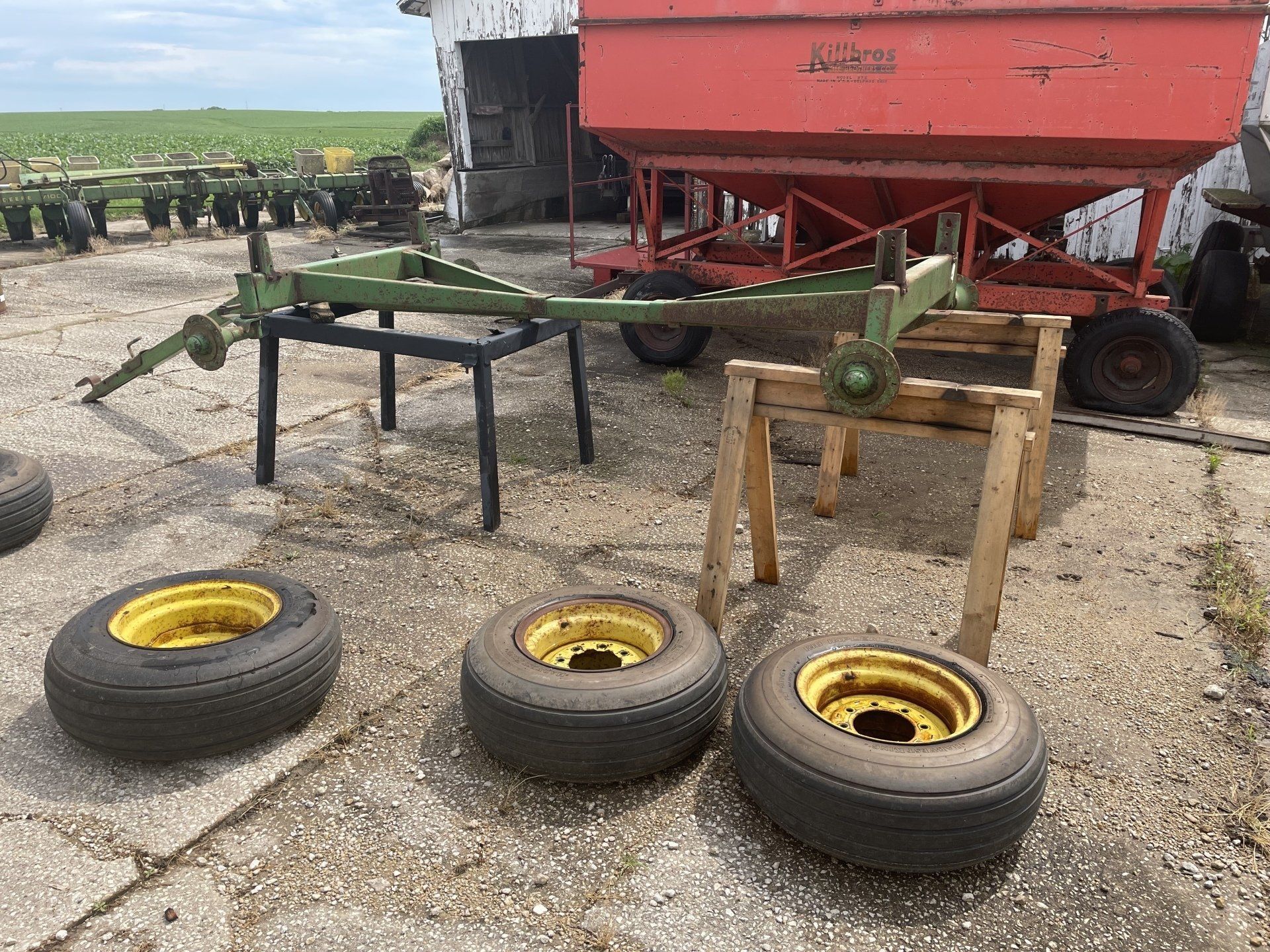a few tires and wheels are sitting on the ground next to a farm trailer