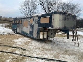 a horse trailer is parked in the snow in a field