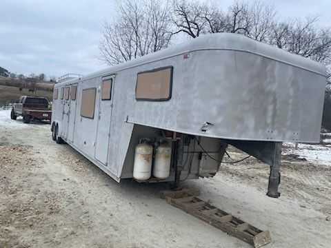 a horse trailer is parked on the side of a dirt road
