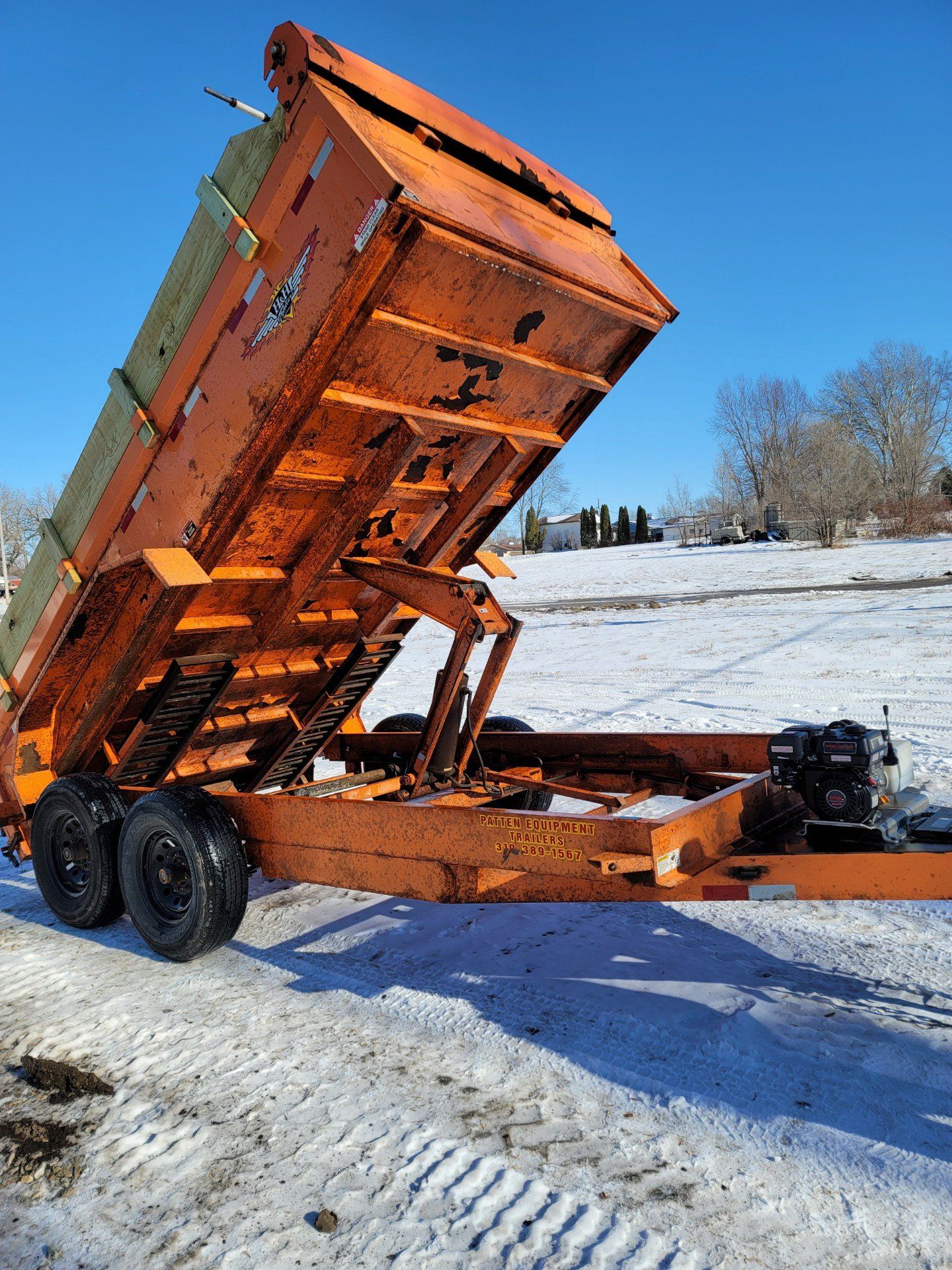 an orange dump trailer is parked in the snow