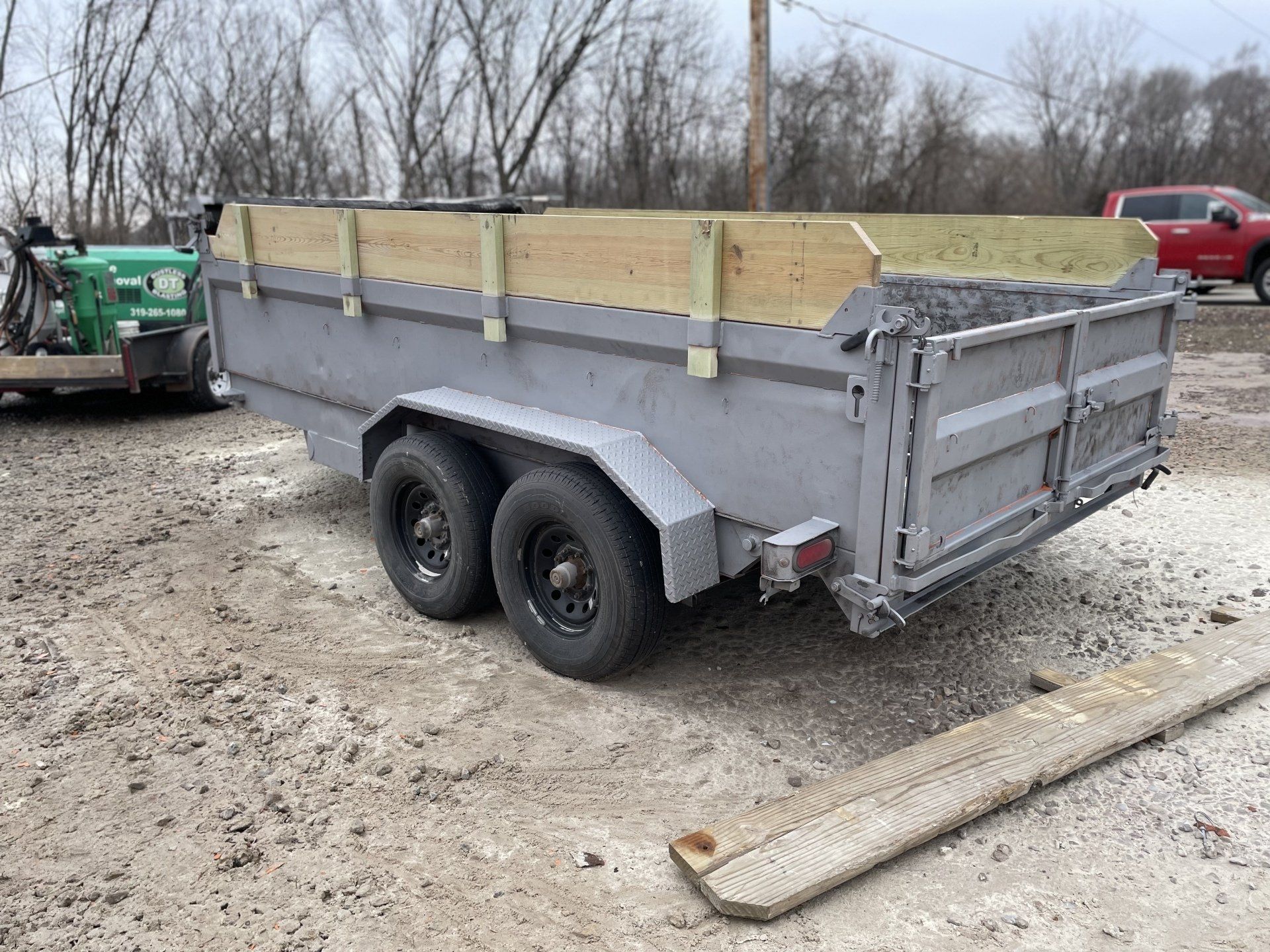 a dump trailer is parked in a dirt lot next to a green tractor