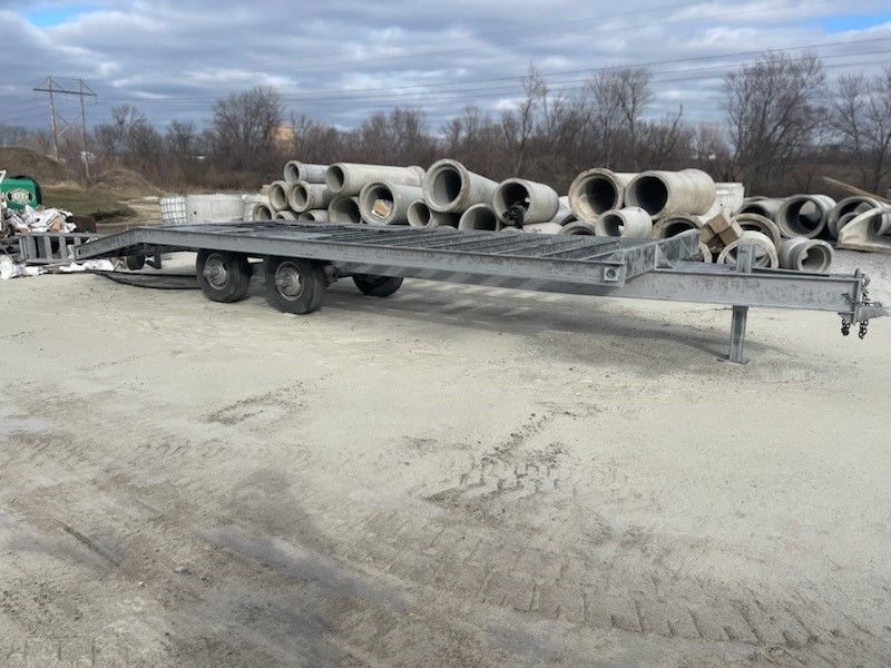 a trailer filled with concrete pipes is parked in a dirt lot