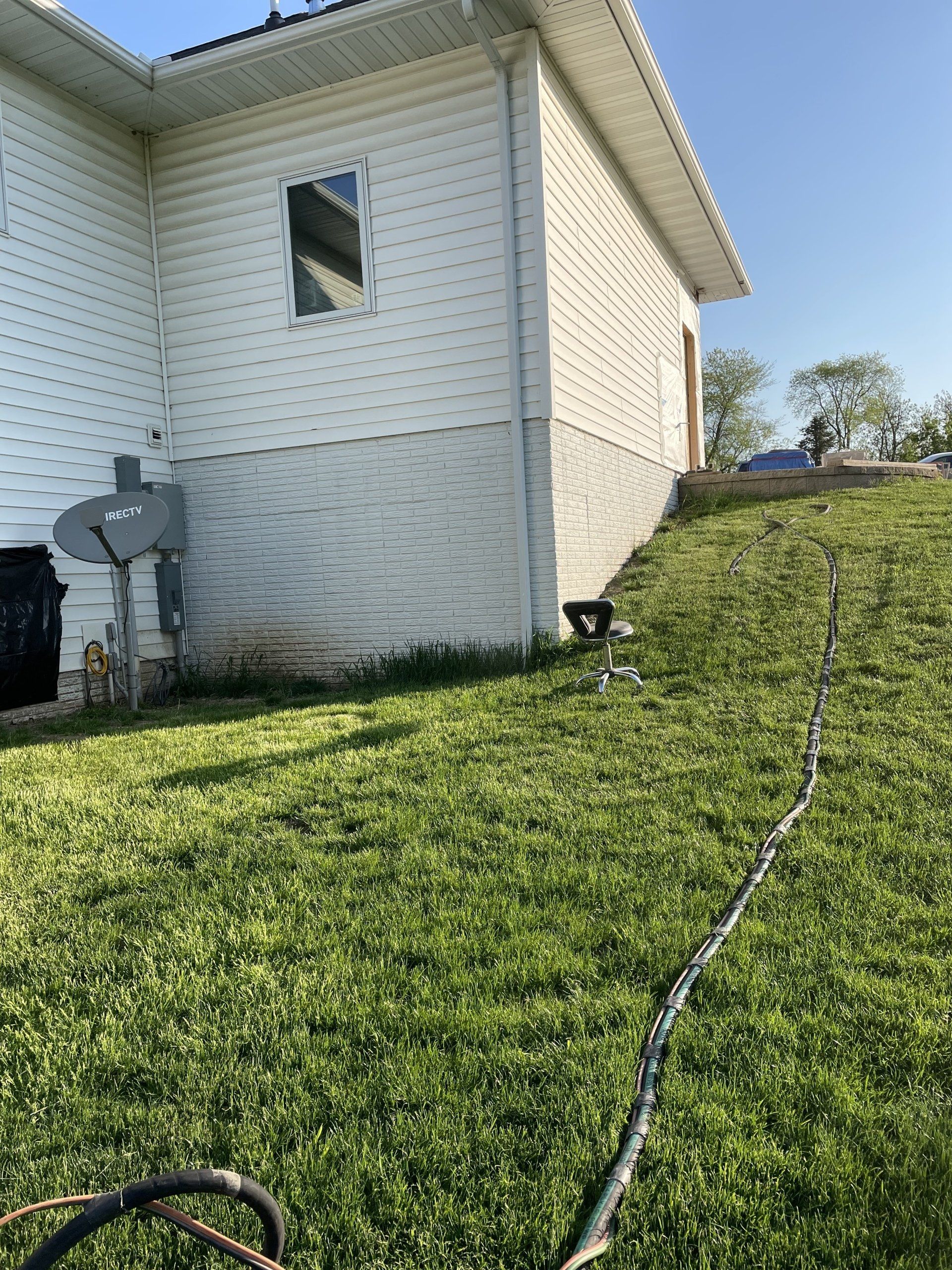 a house with a brick foundation is sitting on top of a lush green hillside