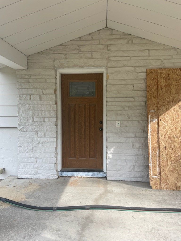 the front door of a house with a brick wall and a wooden door