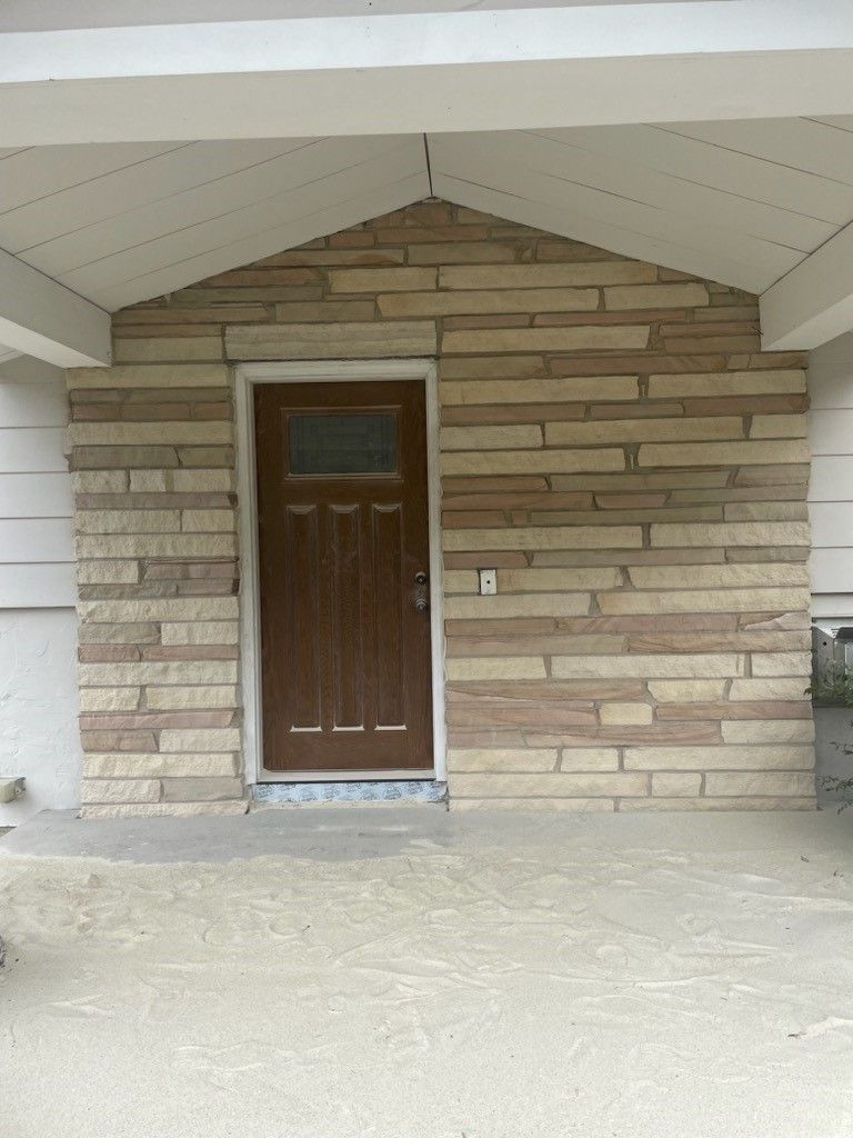 the front door of a brick house with a brown door