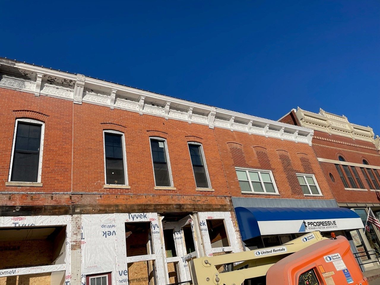 a large brick building under construction with a blue awning
