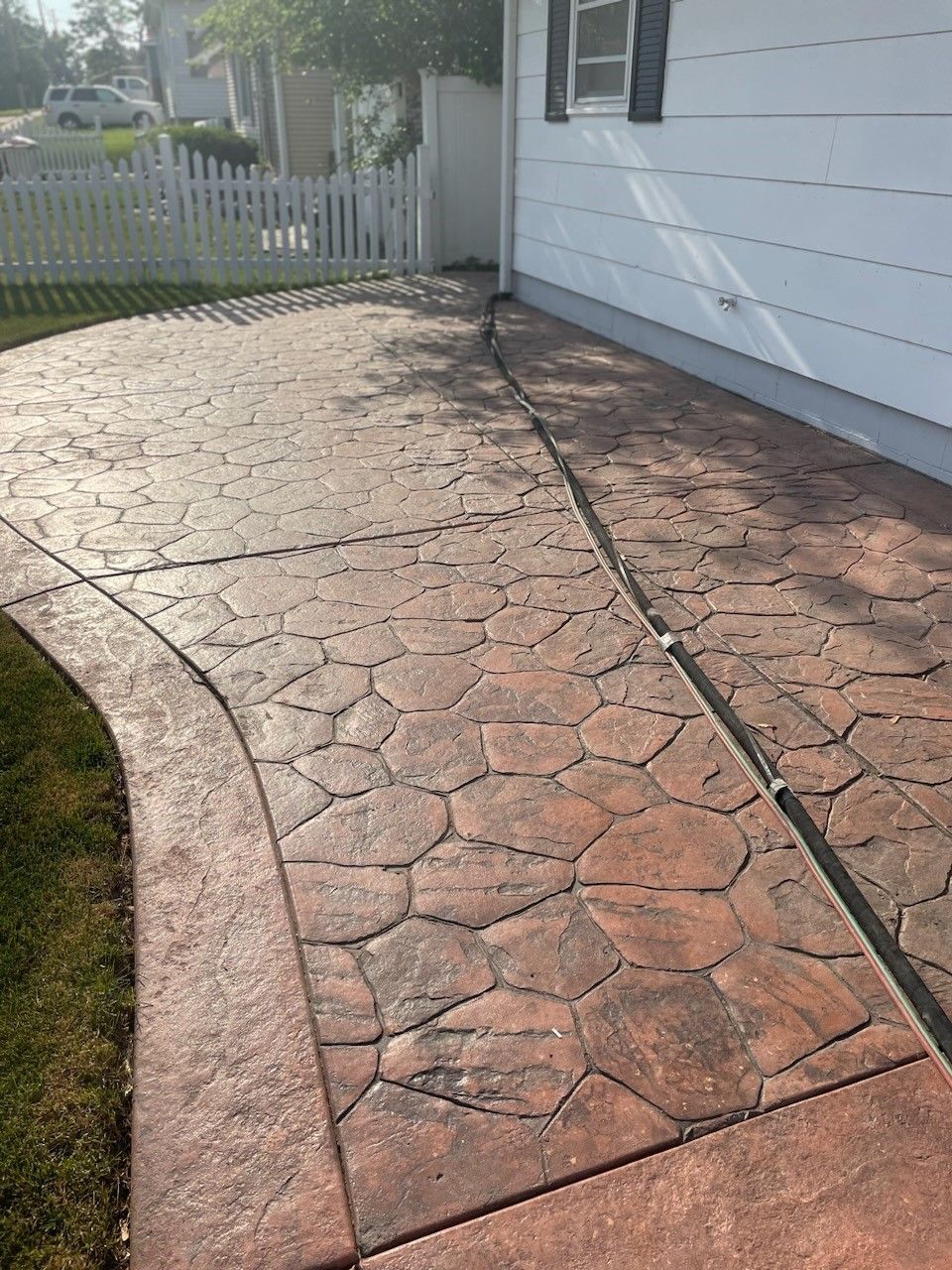 a concrete walkway leading to a house with a white picket fence