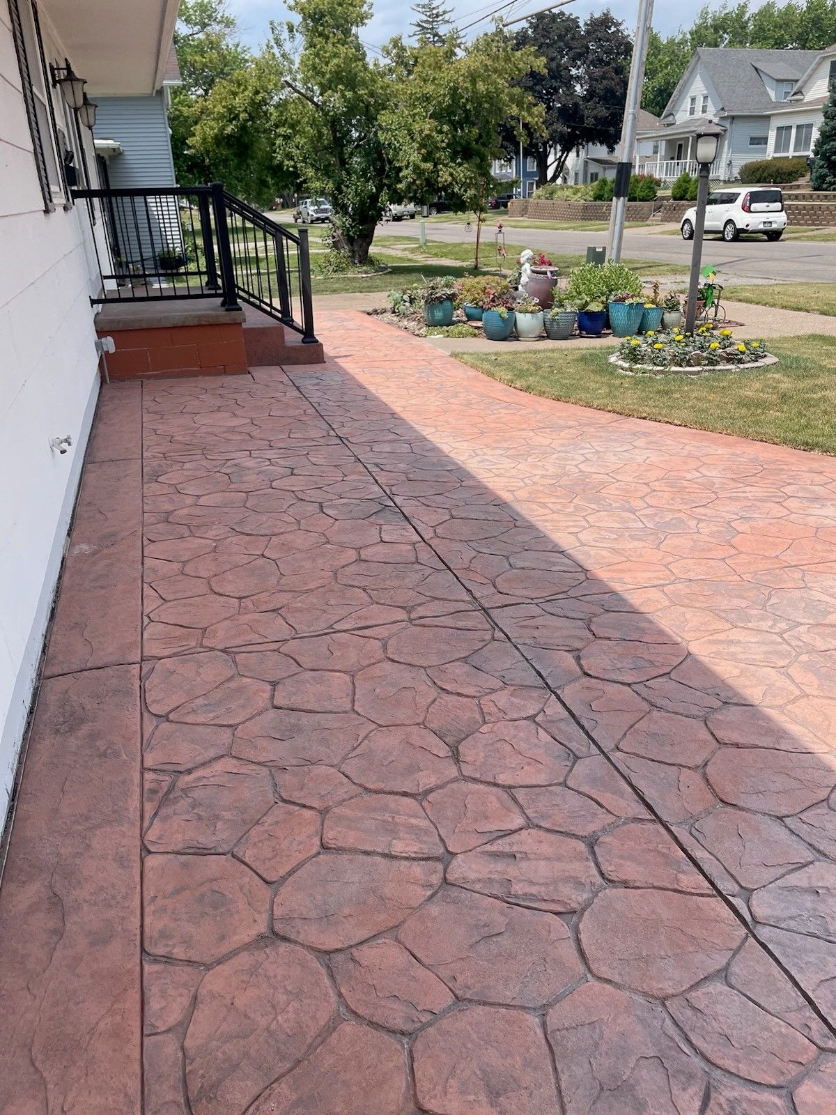a concrete walkway leading to a house with potted plants on the side of it