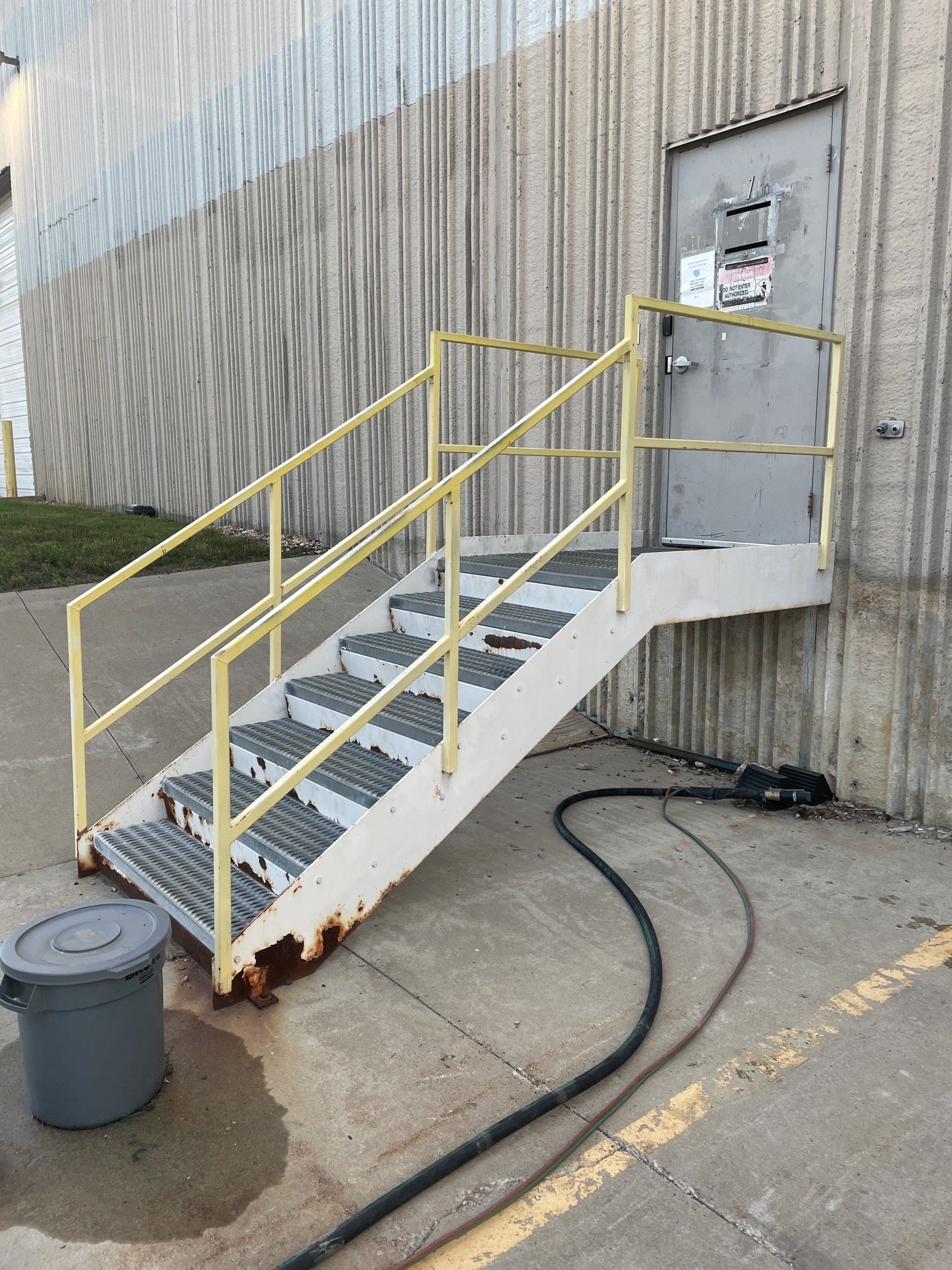 a set of stairs with a yellow railing leading up to a door