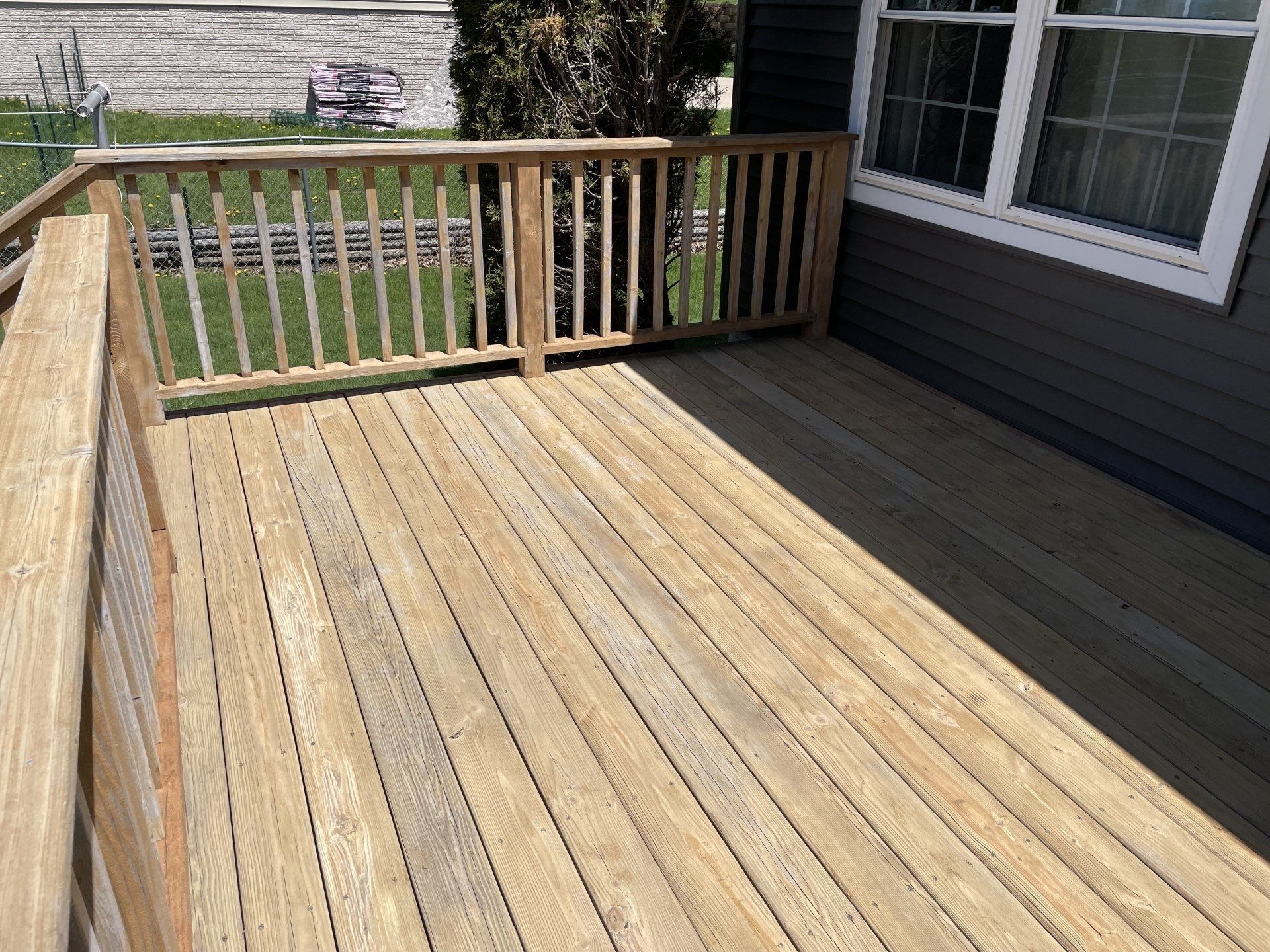 A wooden deck with a railing in front of a house