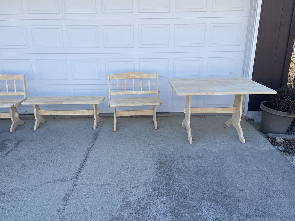 Three wooden benches and a table are sitting in front of a garage door