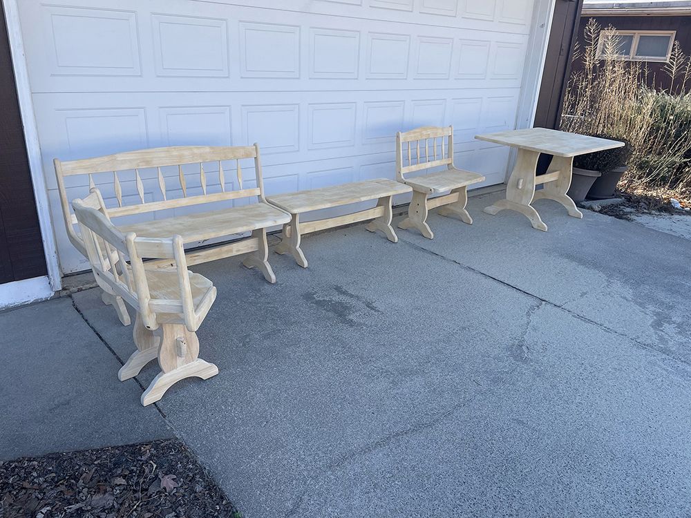 A wooden table and chairs are sitting on a concrete patio in front of a garage door