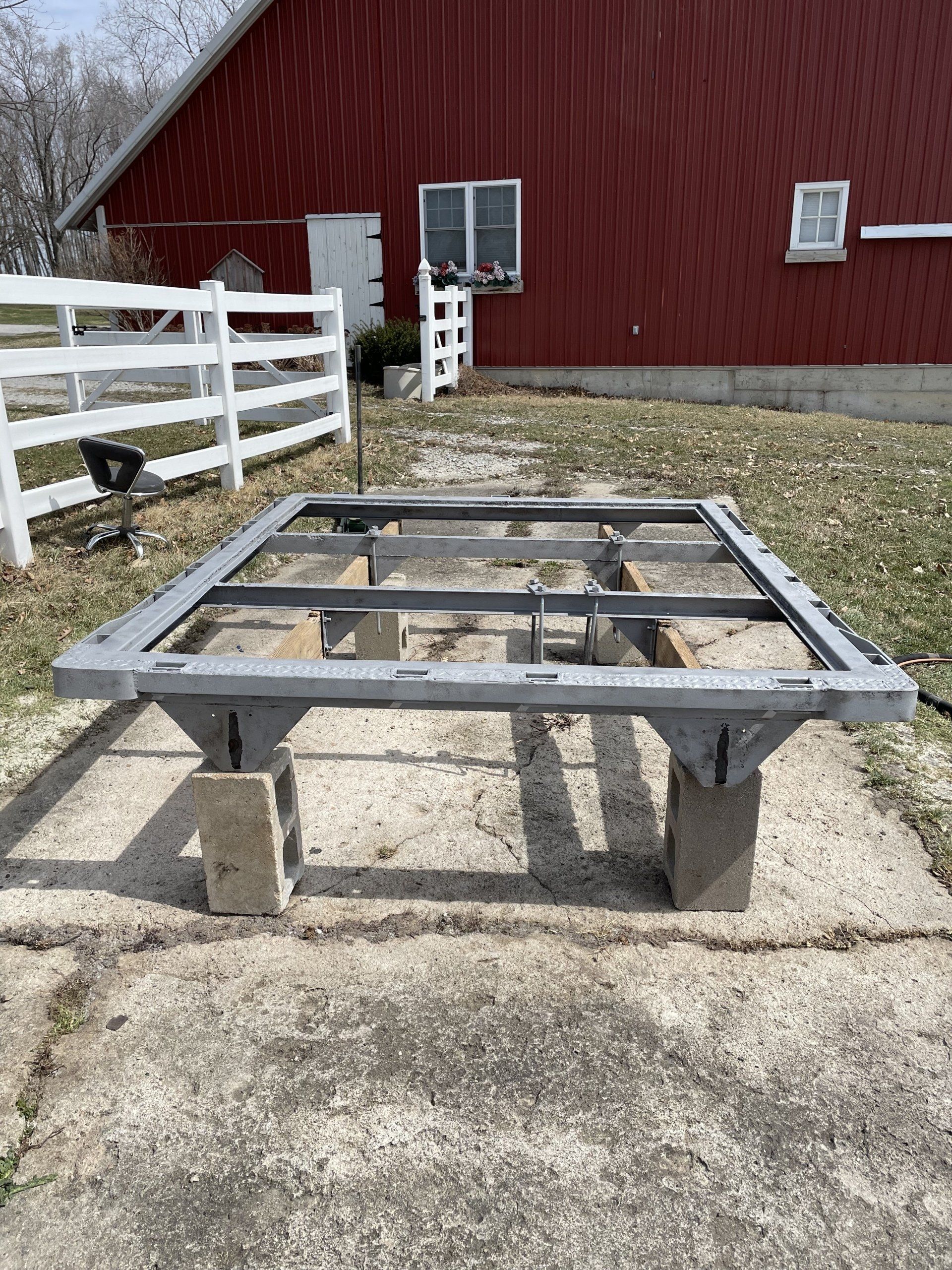 a metal frame is sitting on the ground in front of a red barn