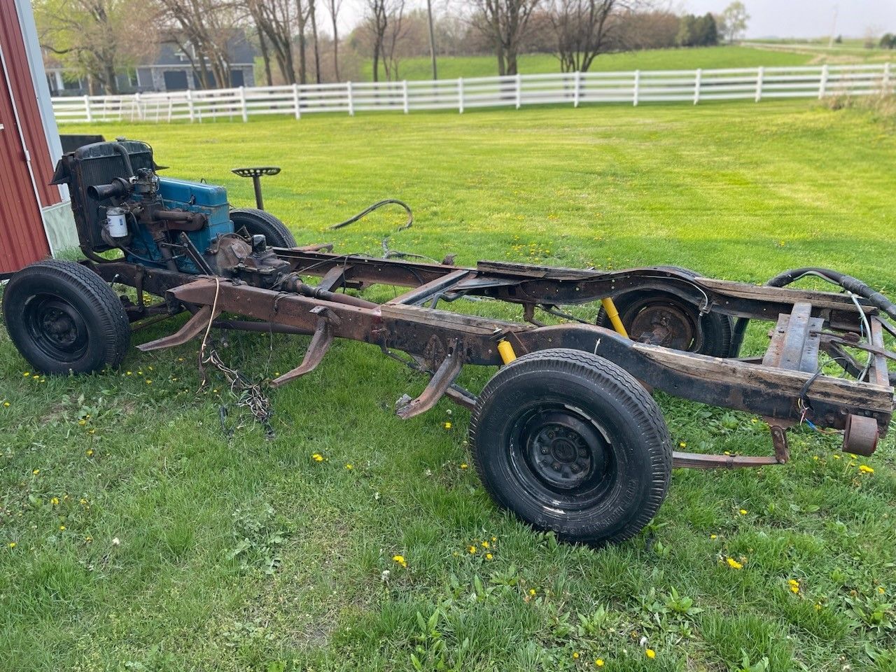 A truck chassis is sitting in the grass in a field