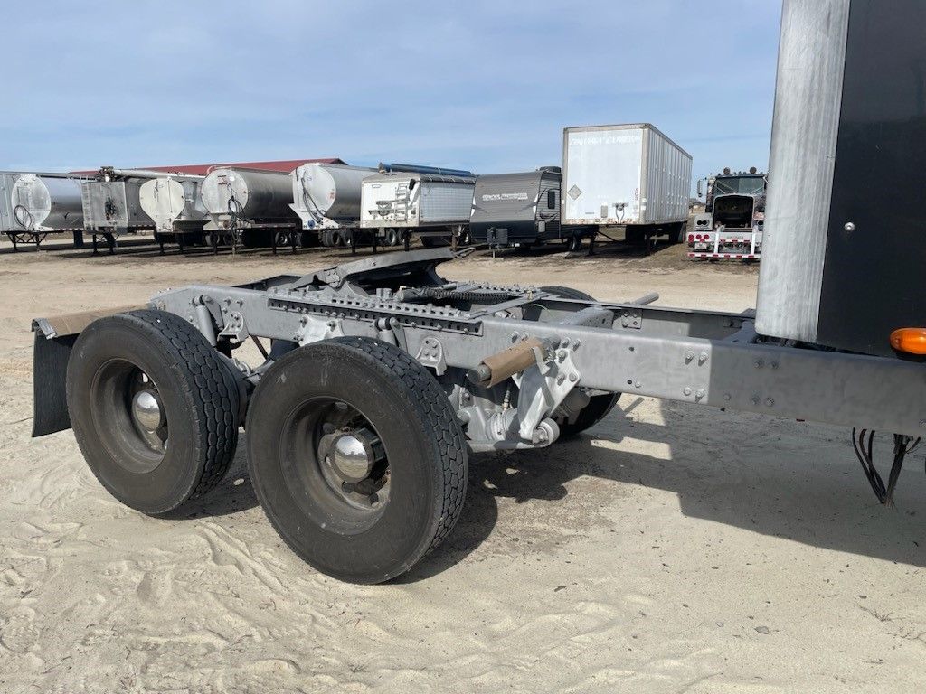A semi truck with a trailer attached to it is parked in the dirt.