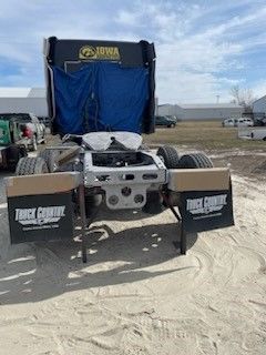 A semi truck is parked in a dirt field.