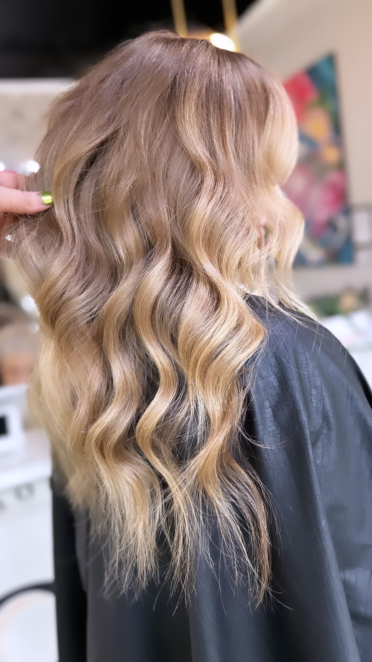Shoulder-length, wavy hair styled in shades of light brown and golden blonde highlights.