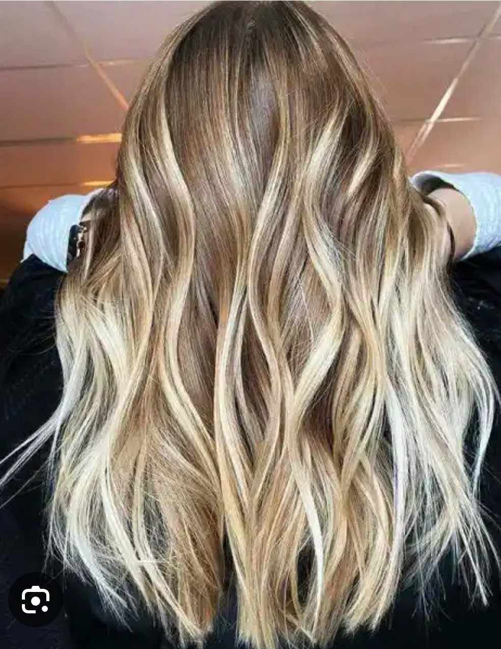 A close-up view of long, wavy hair with blonde highlights transitioning to a brighter, platinum blonde at the ends.