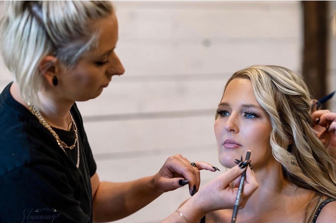 Makeup artist applying lipstick to a woman’s lips in a salon setting