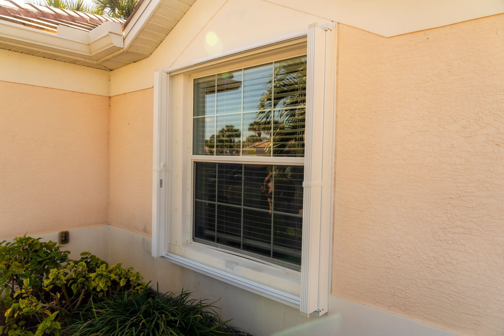 White accordion shutters open on a window