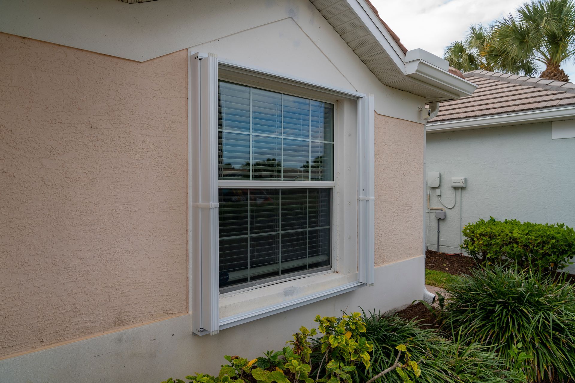 White accordion shutters open on a window