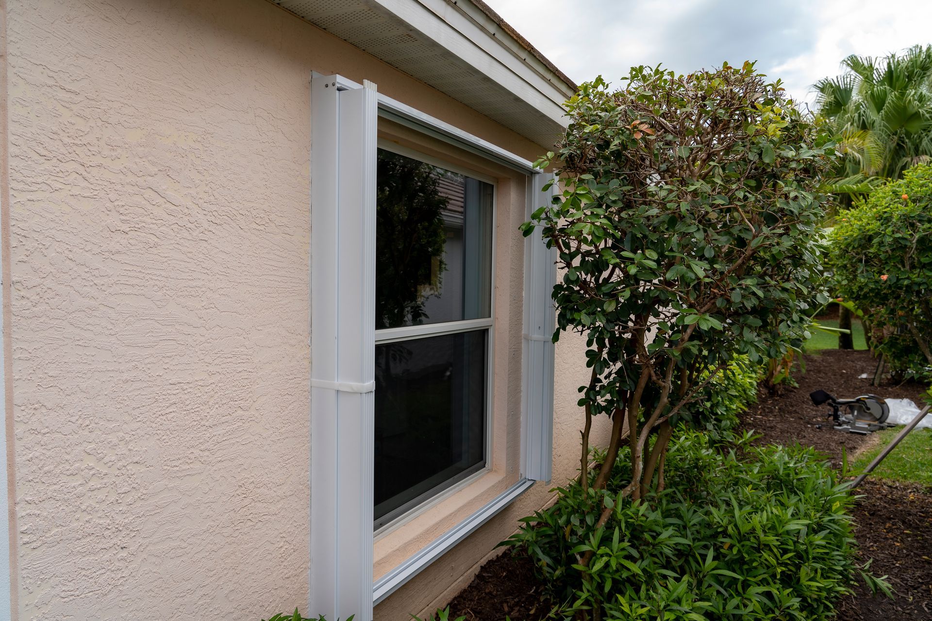 White accordion shutters open on a window