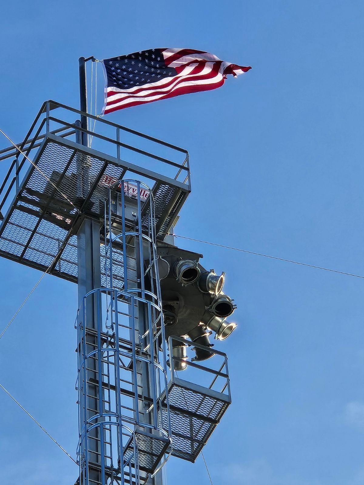 An American flag is flying on top of a metal tower