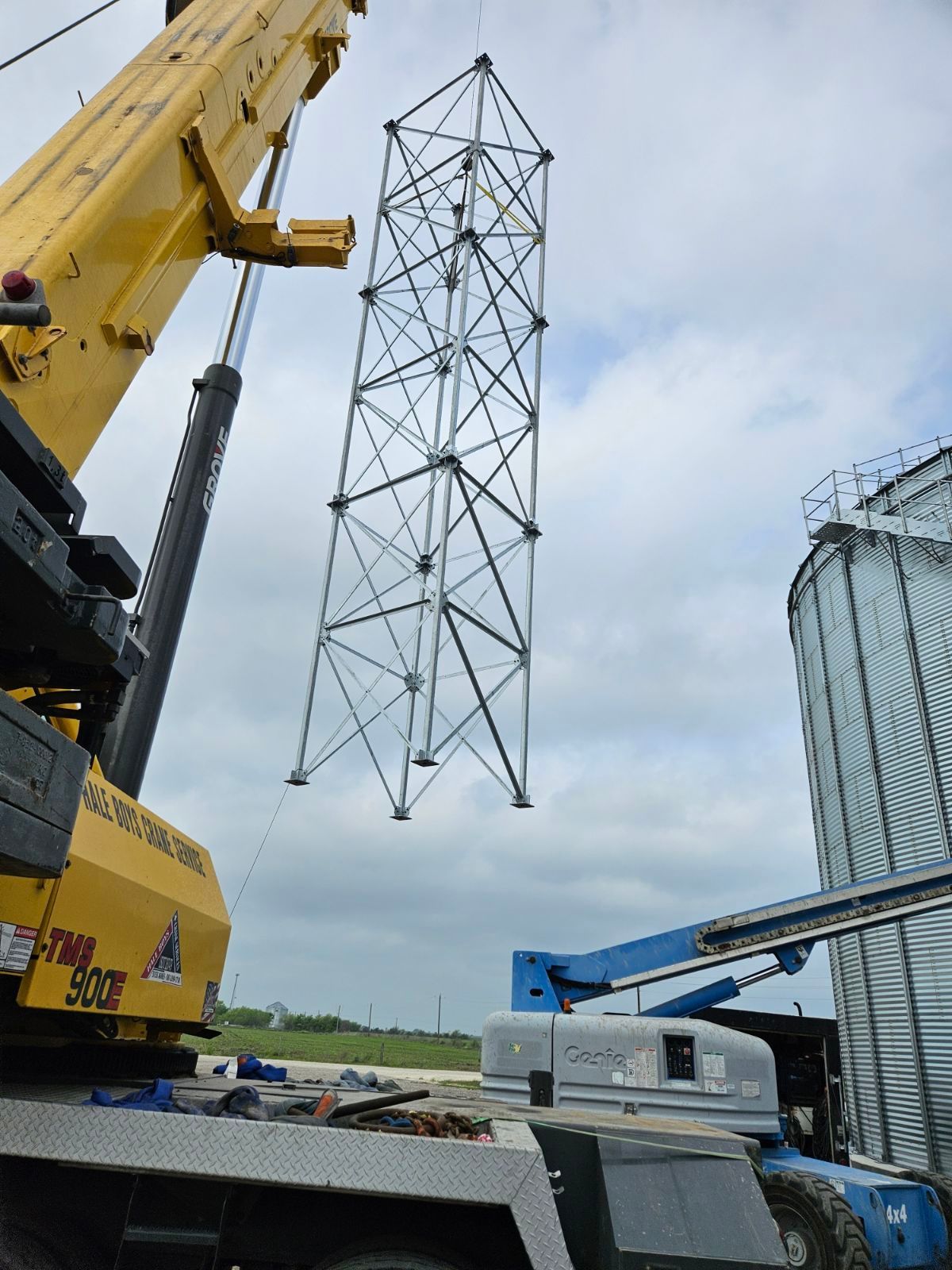 A yellow crane is lifting a tower in the air