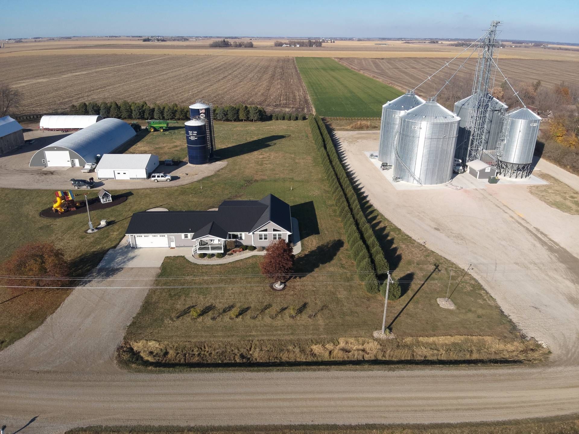 An aerial view of a farm with a house and silos